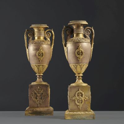 pair of antique bronze urns on pedestals on a black background