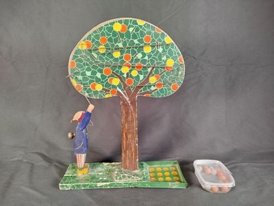 une figurine représentant un homme debout à côté d'un arbre chargé d'oranges