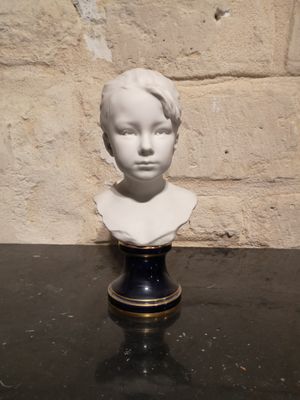 un buste blanc représentant un jeune garçon posé sur une table noire