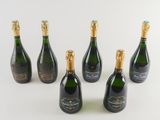 six bottles of champagne are lined up on a white surface