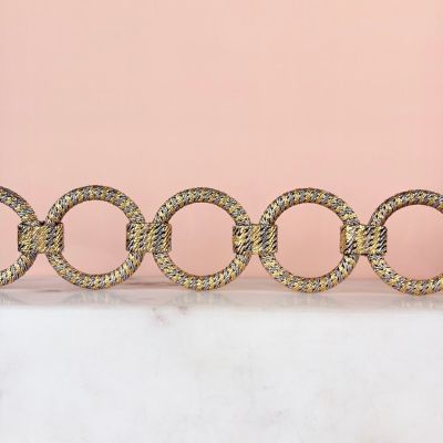 four gold rings on a marble table against a pink background