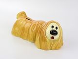 une figurine de chien jaune posée sur une surface blanche