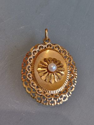 une image représentant un pendentif en or orné d'une perle au centre