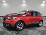 une voiture rouge est garée dans une pièce au sol en damier