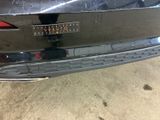the rear end of a black car with a sticker on it
