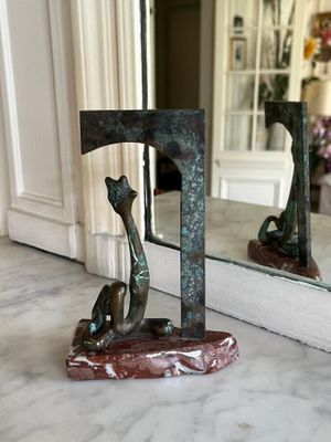 a statue of a cat sitting on a table in front of a mirror