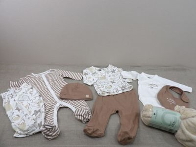 a lot of baby clothes and a bottle on the bed