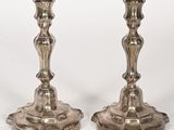 une paire de bougeoirs anciens en argent posés sur des socles, sur fond blanc