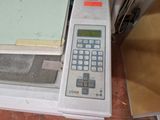 a calculator sitting next to a stack of papers on the floor