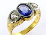 un gros plan d'une bague en or sertie d'une pierre bleue et de deux diamants