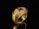 a close up of a gold ring with a red stone in it