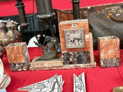une petite horloge posée sur une table, à côté d'autres objets