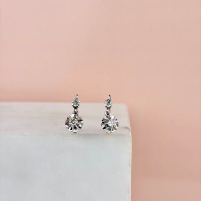 une paire de boucles d'oreilles à clous en diamant posée sur un bloc de marbre