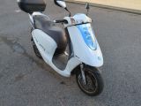 un scooter blanc garé sur le bord de la route
