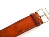 a person holding a brown leather belt with a metal buckle