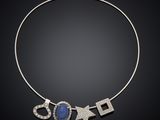 a necklace with a blue stone and diamonds on a black background