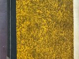 un vieux livre à la couverture jaune posé sur une surface blanche