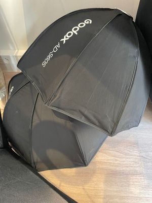 un parapluie noir posé par terre à côté d'une valise