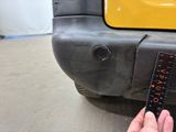 a person measuring the width of a car ' s bumper