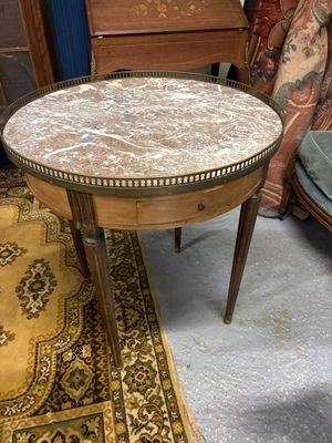 une petite table avec un plateau en marbre posée sur un tapis