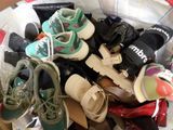 de nombreuses paires de chaussures dans un panier posé sur un lit