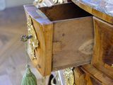 a wooden dresser with a marble top and a tassel hanging from the drawer