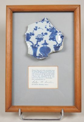 une vieille assiette bleue et blanche, encadrée dans un cadre en bois, sur laquelle est inscrit un poème