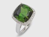 a close up of a ring with a green stone surrounded by diamonds