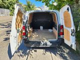 une camionnette blanche dont les portes sont ouvertes, garée sur un parking