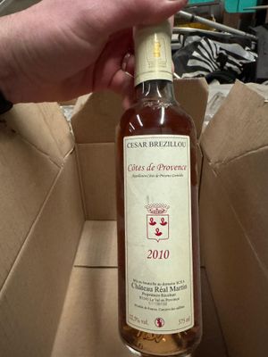 quelqu'un tient une bouteille de vin dans une boîte en carton