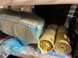 three rolls of fabric wrapped in plastic on a shelf