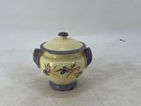 a small ceramic pot with a lid on a white surface