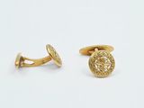 a close up of a pair of gold cufflinks on a white surface