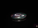 une photo d'un objet en verre noir et vert posé sur une surface noire