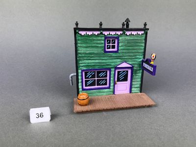 une petite maison verte avec une porte violette et une pancarte sur la façade