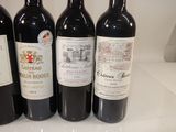 four bottles of red wine are lined up on a counter