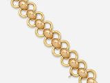 gros plan d'un bracelet en or sur fond blanc
