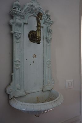 un lavabo dans un coin de la pièce, avec un robinet fixé au mur