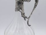an antique silver plated glass pitcher with a floral design on the handle