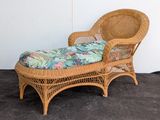 a wicker chaise with a tropical print cushion on it