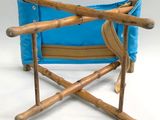 a blue folding chair with bamboo legs on a white background