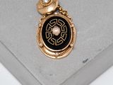 an image of a gold and black broochle on a white surface