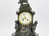 une horloge surmontée d'une statue, posée sur une table