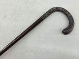 a black cane with a handle on a white surface