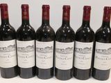 six bottles of red wine lined up in a row on a table