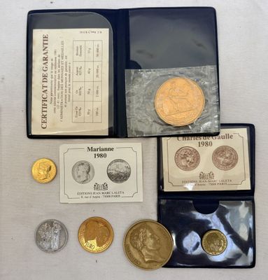 un assortiment de pièces d'or et d'argent, dont l'une se trouve dans un étui noir