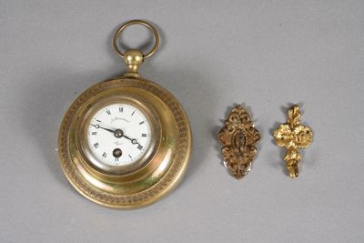 une petite montre de poche en or et une croix posées sur la table