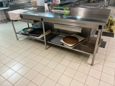 a large stainless steel table in a kitchen with pans and pans on it