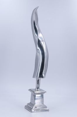 une sculpture en argent représentant une vague, posée sur un socle métallique