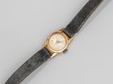 un gros plan d'une montre-bracelet posée sur une surface grise